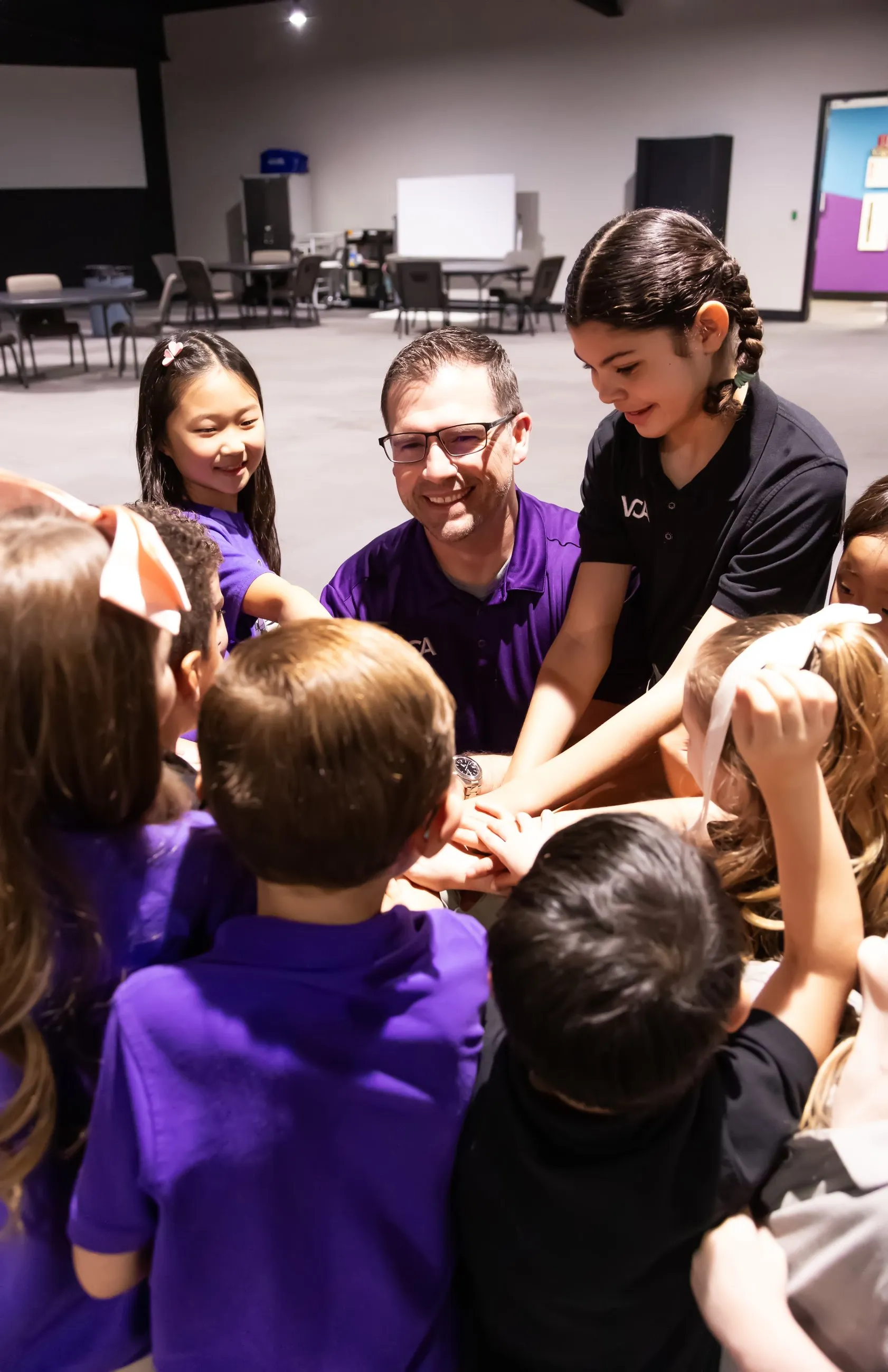 Students and a teacher huddle together, hands joined, at Vintage Christian Academy.